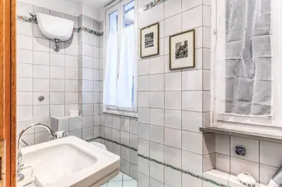 a white tiled bathroom with a sink and a tub at Cozy flat in Trevi Fountain in Rome