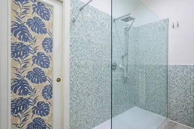 a bathroom with a glass shower with blue tiles at Appartamento via di Torre Argentina (Navona) in Rome