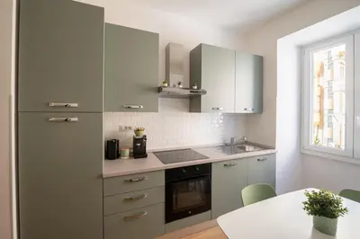 a kitchen with gray cabinets and a sink and a table at Casa M.O.R.E. in Rome