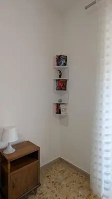 a room with a table and a lamp and a white wall at A casa nostra - Musei Vaticani in Rome