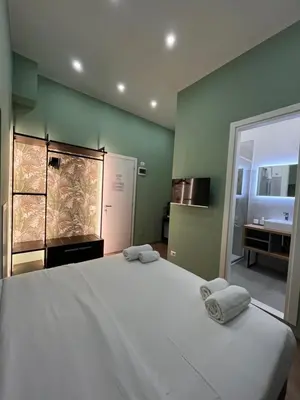 a bedroom with a large white bed and a bathroom at Colosseum Deluxe in Rome