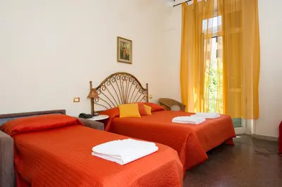 two beds in a room with orange sheets and a window at Boezio House in Rome