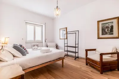 a white bedroom with a bed and a chair at Retro design flat near Vaticano in Rome