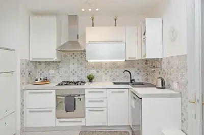 a white kitchen with white cabinets and a sink at Casa Serafina in Prati district in Rome