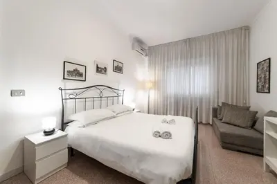 a white bedroom with a bed and a couch at EV Vatican Apartment in Rome