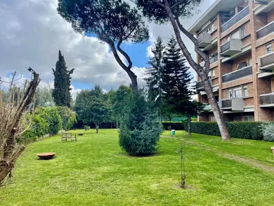 a green yard with trees and a building at Edi's House in Rome