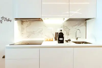 a white kitchen with white cabinets and a bottle of wine at Dolce casa al Vaticano in Rome