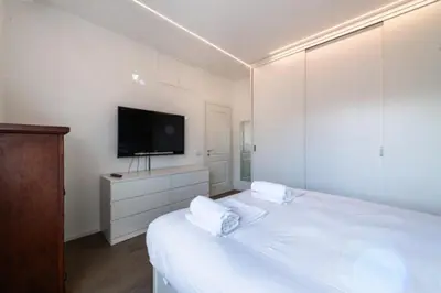 a white bedroom with a bed with a tv on the wall at Time 4 Rome in Rome