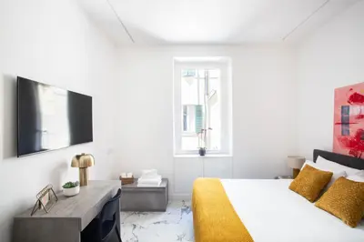 a white bedroom with a large bed with yellow pillows at Romantic Suite Colosseum - Luxury Apartment in Rome