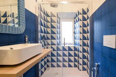 a bathroom with blue and white tiled walls and a sink at Candia Cento Apartment Vatican Museums in Rome