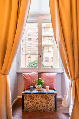 a window with orange curtains and a table with a plant at Piacentino Homes Re di Roma apartment in Rome