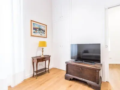 a living room with a flat screen tv and a table at Trastevere Luxury Bright Apartment in Rome