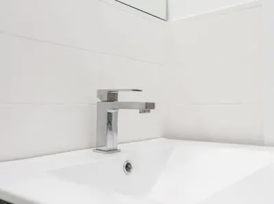 a sink with a faucet on a white wall at Trastevere Luxury Bright Apartment in Rome