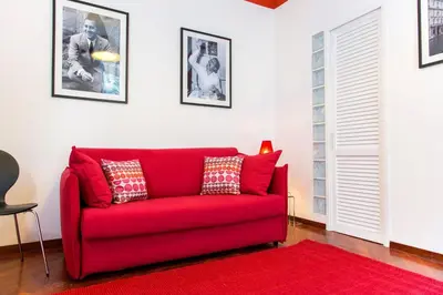 a red couch in a living room with a red rug at Perla - Cozy Apartment in Piazza Navona in Rome