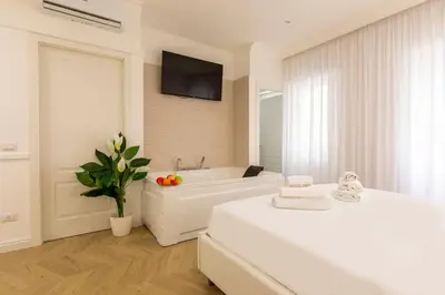 a white bathroom with a tub and a tv on the wall at FARNESINA SUITE in Rome