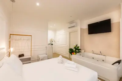 a white bedroom with a large bed and a bath tub at FARNESINA SUITE in Rome
