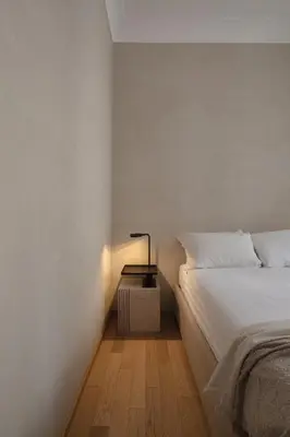 a white bedroom with a bed and a night stand at P10 DESIGN in Rome