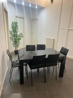 a black dining room table with chairs and a potted plant at Nic trastevere house in Rome