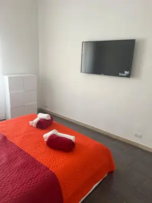 a bedroom with a bed with two red pillows and a flat screen tv at Nic trastevere house in Rome