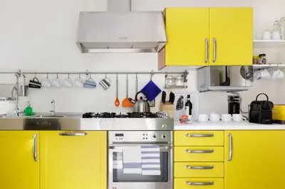 a kitchen with yellow cabinets and a stove at Restart Accommodations Nettuno in Rome