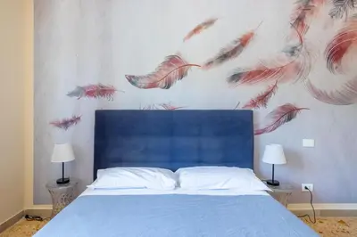 a bedroom with a blue bed with feathers on the wall at Casa Preziosa in Metro Piramide in Rome