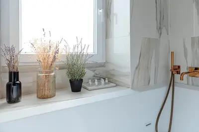 a bathroom counter with flowers and vases on a window sill at Bright and cozy apartment near the Vatican city in Rome