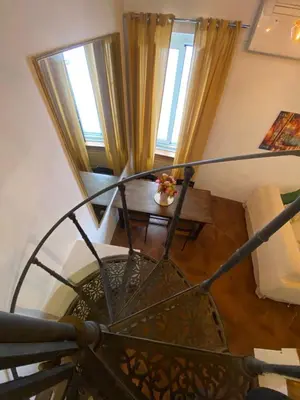 a spiral staircase leading to a living room with windows at Home Bella Roma centro storico in Rome