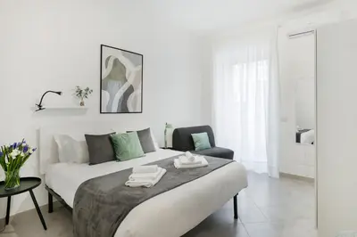 a white bedroom with a large bed and a chair at White Flat San Lorenzo in Rome