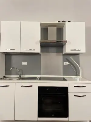 a kitchen with white cabinets and a black oven at Ale home in Rome