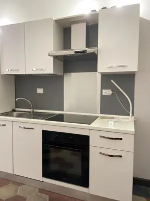 a kitchen with white cabinets and a stove top oven at Ale home in Rome