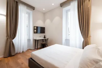 a bedroom with a bed and a desk and windows at Major House - Luxury Apartments in Rome by Hostand in Rome