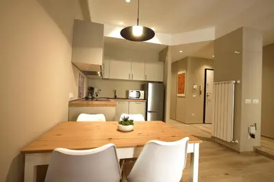a kitchen and dining room with a wooden table and white chairs at Aniene Holiday House in Rome
