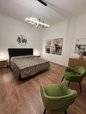 a bedroom with a bed and two green chairs at luna in trastevere apartamento in Rome