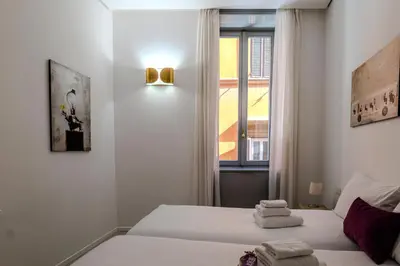 a white bedroom with two beds and a window at Restart Accommodations Trevi in Rome