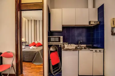 a kitchen with white cabinets and a red chair at M&L Apartments - Ardesia Colosseo in Rome