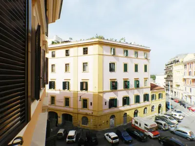 a tall white building with cars parked in a parking lot at Movie Apartment in Rome