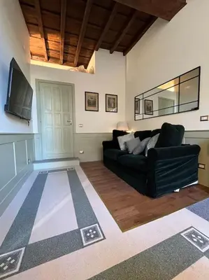 a living room with a black couch and a tv at Boutique Signature Suite in the Heart of Ancient Rome in Rome