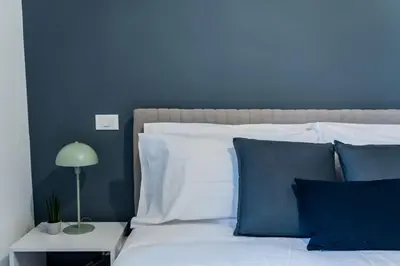a blue bedroom with a white bed with blue walls at Domina Apartments Roma - San Pietro 1 in Rome