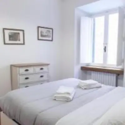 a white bedroom with a bed and a dresser and a window at Welcome to the ColosseHome in Rome