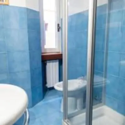 a blue bathroom with a shower and a toilet at Welcome to the ColosseHome in Rome