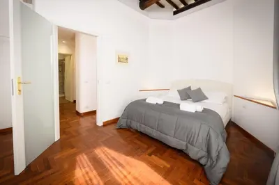 a white bedroom with a bed and a wooden floor at Mommy's - Vatican House in Rome