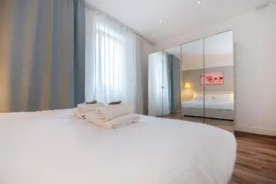 a bedroom with a white bed and a mirror at COLOSSEUM VIEW ACCOMODATION in Rome