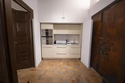 a kitchen with white cabinets and a wooden door at Via Giulia Charming Apartment with Balcony in Rome