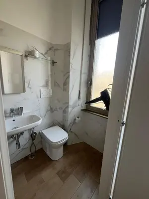 a white bathroom with a toilet and a sink at Camera singola con vista su San Pietro in Rome