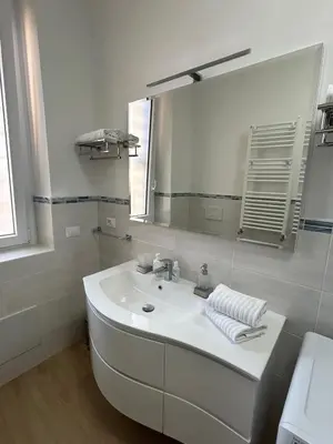 a white bathroom with a sink and a mirror at Casa Riboty by GHOR in Rome