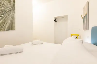 a white bedroom with a white bed and a mirror at Trastevere Exclusive Three Bedroom Apartment in Rome