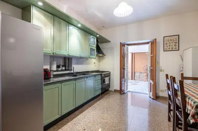 a kitchen with green cabinets and a refrigerator at Maximo Luxe -Villa & Apartment in Rome