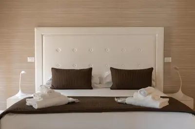 a white bed with two towels on top of it at Blue Inn Luxury Suites in Rome