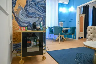 a living room with blue walls and a table and chairs at Via Veneto 116 Suites - Guest House in Rome