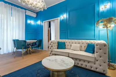 a living room with blue walls and a couch and a table at Via Veneto 116 Suites - Guest House in Rome